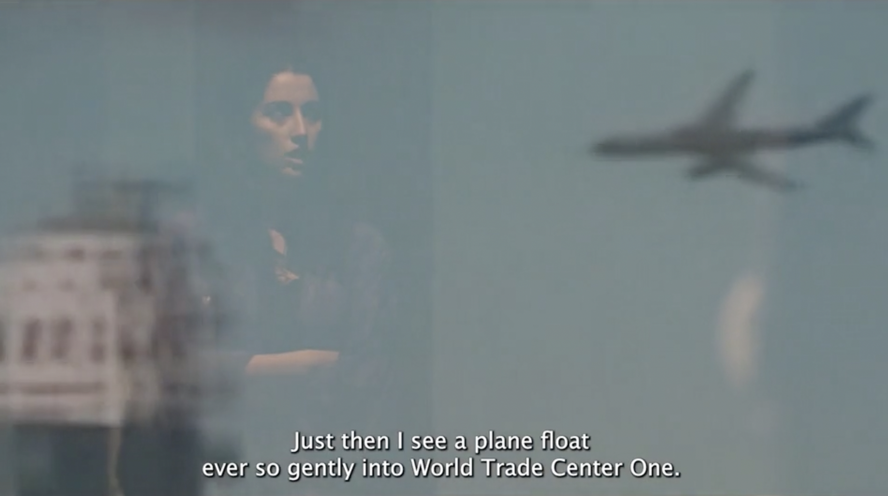 actor speaking with image of a plane flying into a tower in the background