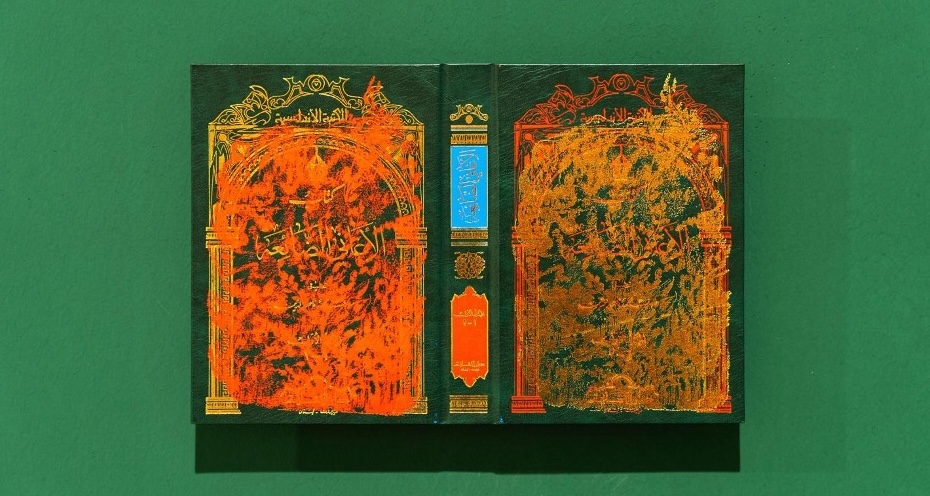 spread open book covers, painted with yellow and orange. Photographed on a green background