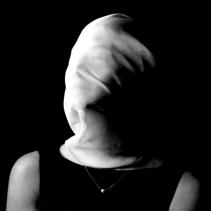 monochrome photograph of a woman with a transparent white scarf covering her face