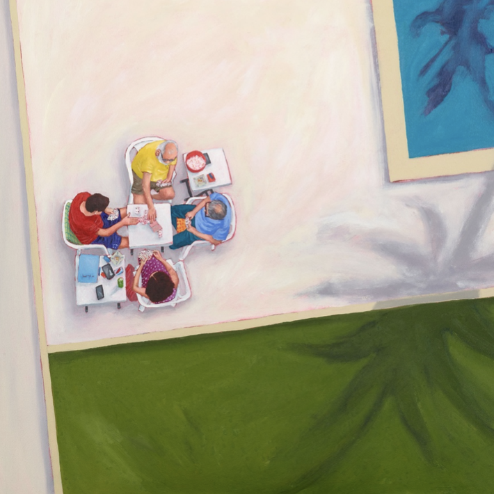 Viewed from above: 4 people at a table beside a pool. 